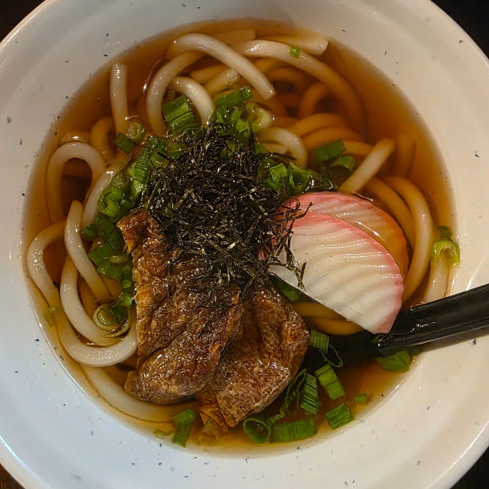Close-up of Yatai Ramen's udon noodle soup with fried tofu, green onions, nori, and fish cake.