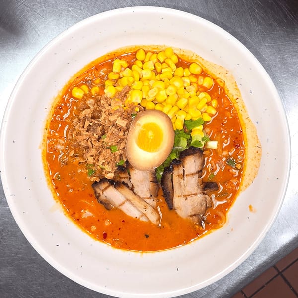 Yatai Ramen's spicy ramen bowl with pork belly, corn, fried onions, and a soft-boiled egg.