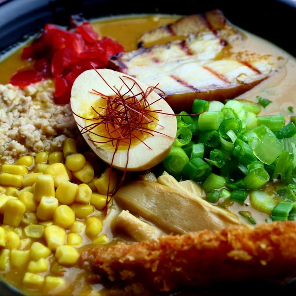 Close-up of Yatai Ramen with grilled pork, egg, corn, green onions, and red ginger.
