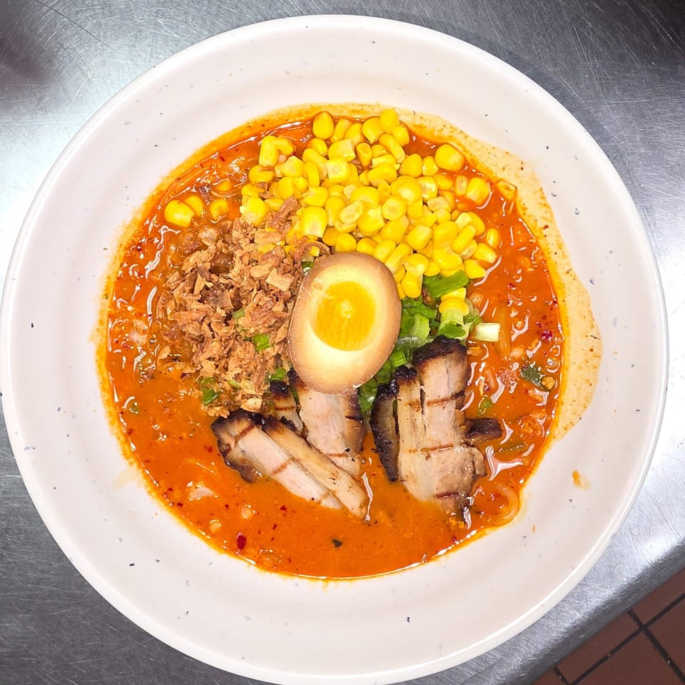 Yatai Ramen's spicy ramen bowl with pork belly, corn, fried onions, and a soft-boiled egg.